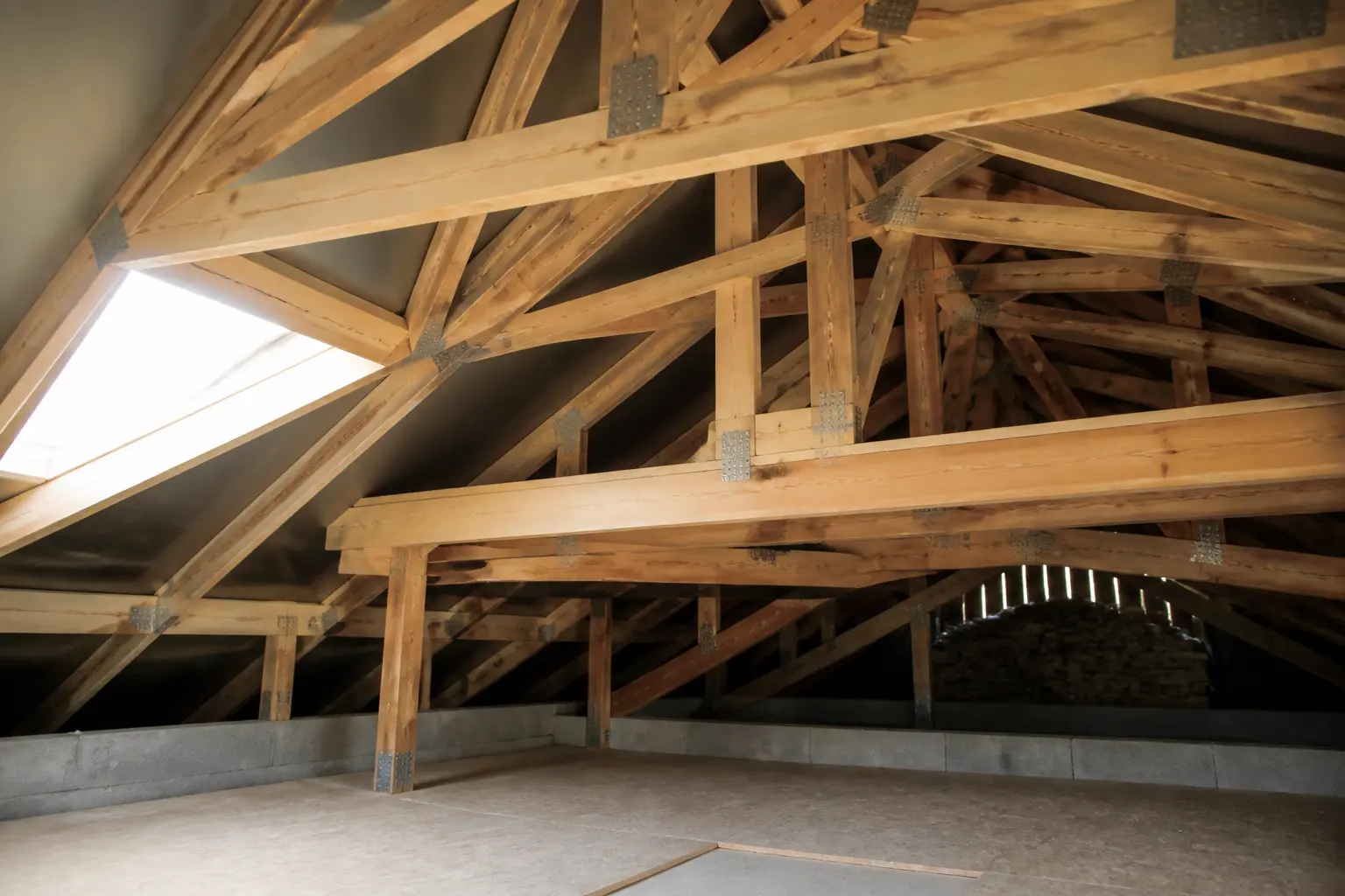 Charpente à fermette en bois d’une maison moderne, vue intérieure du toit avec combles partiellement aménageables.