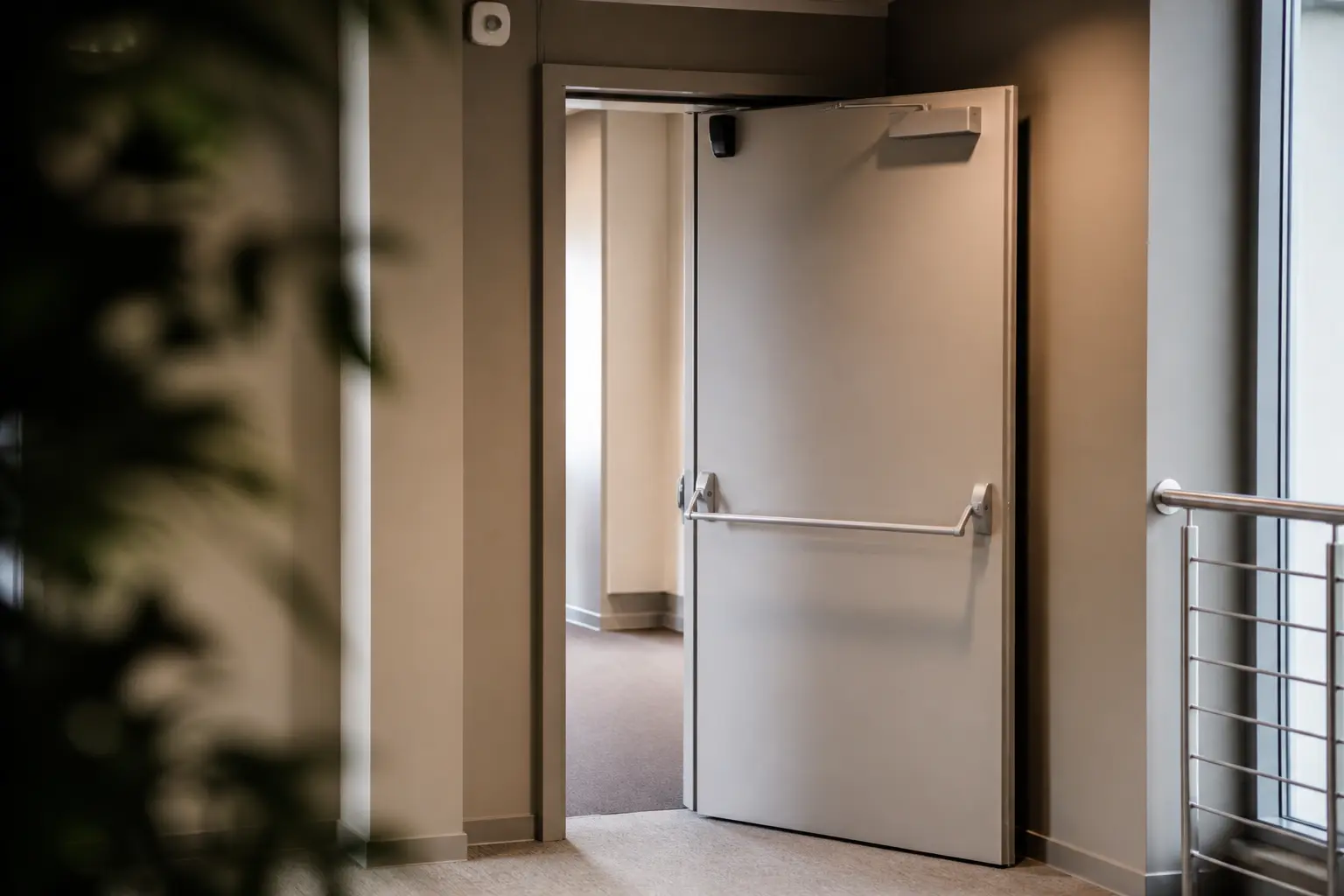 Porte das coupe-feu ouverte dans un couloir d’immeuble moderne, avec dispositif de maintien et fermeture automatique visible