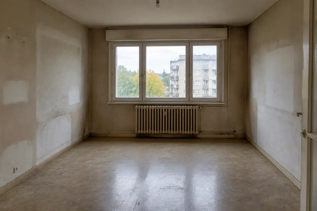Séjour vide d'un appartement social entre deux locataires, radiateur sous la fenêtre