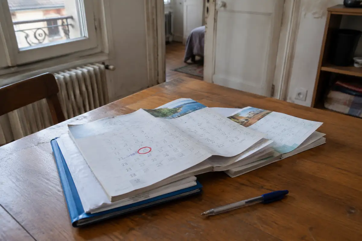 Calendrier papier avec une date entourée posé sur un dossier immobilier