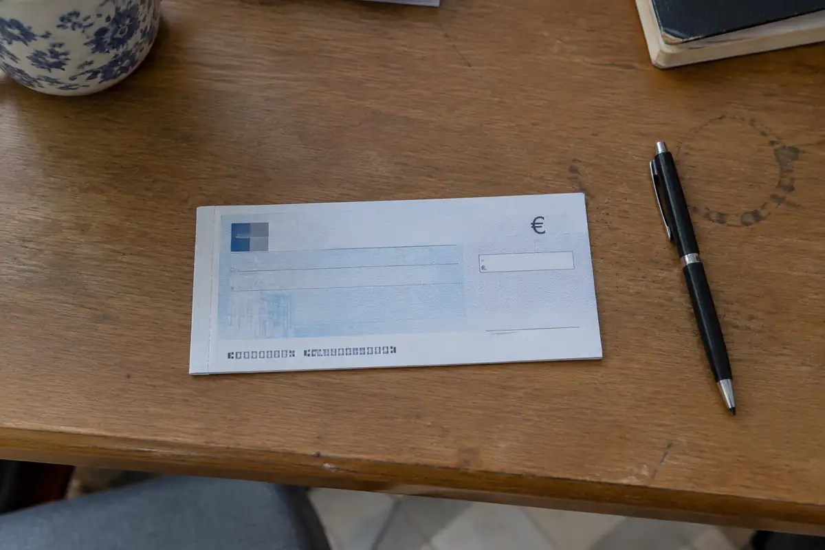 Chèque vierge posé près d'un stylo sur un bureau en bois