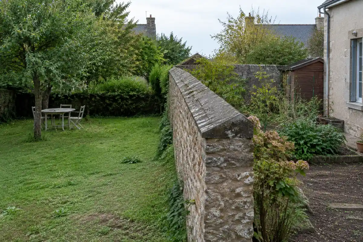 Mur de pierre à chaperon à deux pentes séparant deux jardins